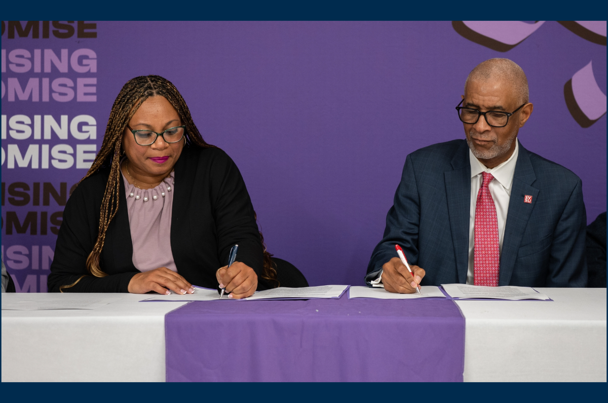 Woman and man signing documents in front of purple backdrop